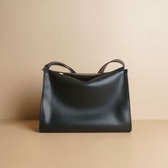 A relatively simple shaped leather shoulder bag. Vintage gold metal fittings and zippers create an elegant atmosphere. Made of soft cowhide leather, it feels good to the touch. There is a pocket inside. 
 
 
 Color 
 
 Black 
 Brown 
 
 
 Size 
 
 Height: 21cm 
 Width: 31cm 
 gusset: 13cm 
 Rise: 35-48cm 
 
 
 Material 
 
 Cowhide Elegant Solid Hobo Bag For Office, Sleek Satchel Shoulder Bag With Gold-tone Hardware, Sleek Top Handle Shoulder Bag With Smooth Grain, Sleek Shoulder Bag With Top Handle And Smooth Grain, Formal Shoulder Bag With Large Capacity, Minimalist Shoulder Bag With Gold-tone Hardware, Elegant Solid Hobo Bag With Zipper Closure, Minimalist Soft Leather Clutch Shoulder Bag, Sleek Soft Leather Crossbody Shoulder Bag