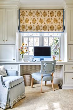 a chair and desk in front of a window with a computer on top of it