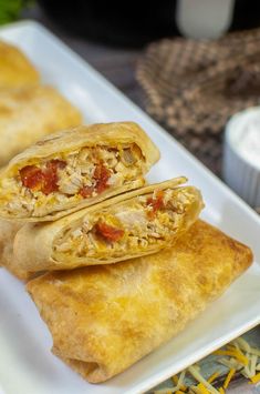 two burritos on a white plate with cheese and tomato sauce in the middle