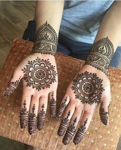 two hands with henna tattoos on them