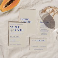 the wedding stationery is laid out on top of white paper with a slice of papaya next to it