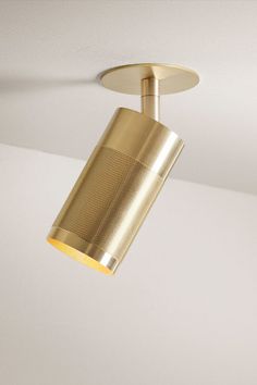 a gold colored light fixture hanging from the ceiling in a room with white walls and flooring