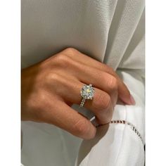 a woman's hand with a diamond ring on her finger, wearing a white dress