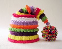 a multicolored crocheted hat with a pom - pom attached to it