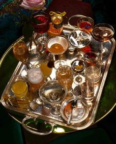 a tray filled with different types of glasses on top of a green tableclothed surface