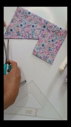 someone is cutting fabric with scissors on a white surface and another person is holding a pair of scissors in front of them