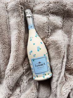 a bottle of lancra sitting on top of a bed covered in fluffy blankets