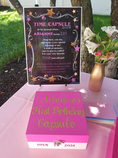 a pink birthday cake sitting on top of a table next to a sign that says time capsule ariane 2011