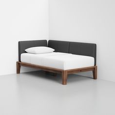 a bed with two pillows on top of it and a white wall in the background