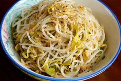 a bowl filled with noodles and vegetables on top of a wooden table next to a fork