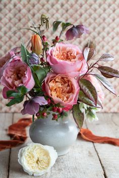 a vase filled with lots of flowers on top of a wooden table next to an egg shell