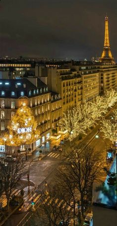 the eiffel tower is lit up at night with christmas lights in the foreground