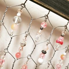 a bunch of beads are hanging on a chain link fence that's attached to a wooden board