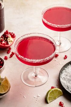 two glasses filled with red liquid and garnished with pomegranates