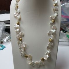 24 karat yellow gold toggle clasp and accented gold beads adorn this keshi pearl necklace. The necklace is 22 inches long including the clasp ends. The pearls are keshi pearls there are not cultured. The color and luster of the pearls are outstanding. The pearls are white, bright luster and white with rose overtone. The pearls measure 14 mm - 15 mm across. There are 8 round 24 karat flat circular beads in the necklace and are high polished. The gold beads measures 10 mm across. I strung the neck Gold Mother Of Pearl Necklace With Pearl Drop, Gold Pearl Necklace With Mother Of Pearl Charm, Gold Pearl Necklace With Pearl Charm, Yellow Gold Baroque Pearl Single Strand Necklace, Gold Single Strand Mother Of Pearl Jewelry, Gold Beaded Baroque Pearl Necklace, Yellow Gold Pearl Necklace With High Luster Baroque Pearls, Gold Baroque Pearl Beaded Necklace, Yellow Gold High Luster Baroque Pearl Necklace