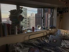 a laptop computer sitting on top of a bed next to a window filled with books