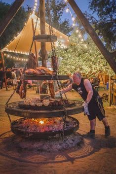 a man standing in front of a large grill with meat on it's sides