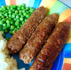 there are three sausages on the plate with mashed potatoes and peas