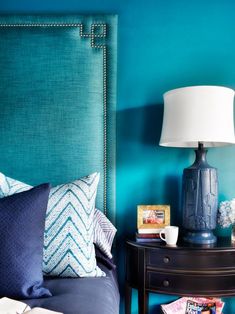 a blue headboard in a bedroom next to a night stand with books on it