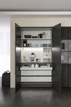 an open cabinet in the middle of a room with black and white furniture on it