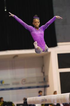 a person jumping in the air while wearing a purple leotard and doing gymnastics