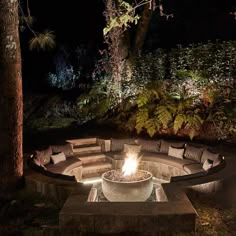 an outdoor fire pit surrounded by trees at night