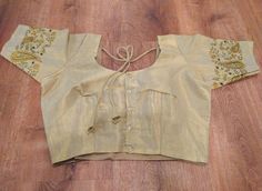 A pretty choli blouse in light gold soft tissue cotton with contrasting designs embroidered on the sleeves.  A choli is basically an Indian version of a crop top, traditionally worn with a saree or skirt but can also be paired with jeans or however suits you.  It has lining, is button up, has tie strings with pretty tassels at the back and short sleeves. It is available in size medium, which fits a 37-38 inch bust - with a few inches inseam - enough to adjust it up a little bigger should you need.  Please note that due to the nature of digital photography the colors may vary slightly in that they may be more vibrant or muted than the image. Gold Chanderi Blouse For Transitional Seasons, Transitional Gold Chanderi Blouse, Fitted Embroidered Beige Choli, Fitted Beige Choli For Festive Occasions, Festive Fitted Beige Choli, Festive Beige Fitted Choli, Festive Embroidered Cotton Silk Choli, Festive Embroidered Beige Choli, Festive Beige Embroidered Choli