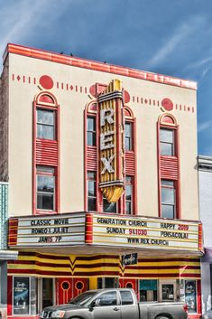 an old movie theater with cars parked in front and the marquee painted red