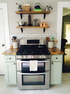 a stove top oven sitting inside of a kitchen next to wooden shelves and open shelving