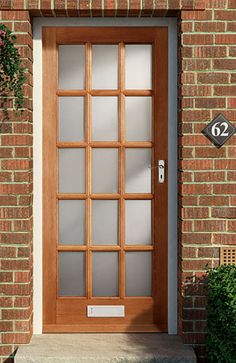 the front door is made of wood and has glass panels on each side, along with a brick wall