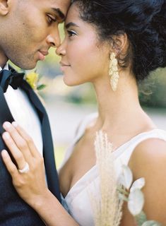 a man and woman in formal wear standing next to each other with their arms around each other