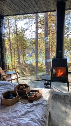 a bed in front of an open fire place next to a forest filled with trees