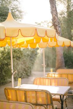 an outdoor dining area with yellow chairs and umbrellas