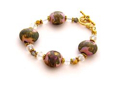 "Jewelry Gift for Her/Gifts for Her 8 inch Handmade pink and gold lampwork bracelet contains dusty pink lentil shaped lampwork beads with golden swirls. The beads are spaced by clear and metallic gold faceted Czech crystals and gold finished pewter spacers. Closes easily with a gold plated toggle clasp with floral decoration. Length: 8 inches Please leave a note if you need a small adjustment in length. Arrives with a Marty White card in a lovely decorative bag and bubble wrap packaging. Follow Pink Czech Glass Bracelets With Faceted Beads, Pink Czech Glass Bracelets With Spacer Beads, Adjustable Pink Bracelets, Handmade Pink Czech Glass Bracelets, Pink Czech Glass Bracelet, Pink Jewelry With Spacer Beads For Jewelry Making, Pink Beaded Bracelet, Lampwork Bracelets, Pink Beaded Bracelets