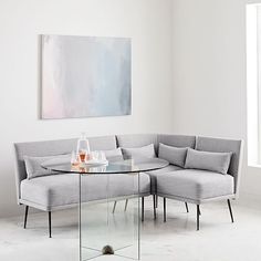 a glass table sitting on top of a white couch next to a gray sectional sofa