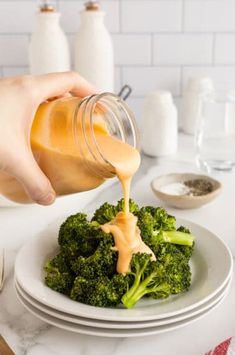 a person pouring dressing onto a plate of broccoli