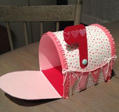 a pink and white mailbox with hearts on it