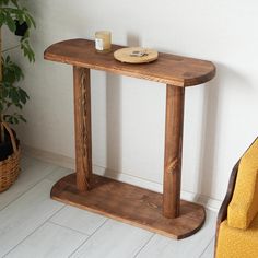 a wooden table sitting next to a yellow chair and potted plant in a corner