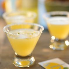 two glasses filled with yellow liquid sitting on top of a table next to playing cards