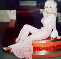 a woman sitting on top of an orange and silver object with her legs spread out