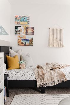 a bedroom with white walls and pictures on the wall above the bed, along with a teddy bear