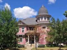 a large pink house with trees in the front yard