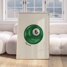 a green pool ball sitting on top of a wooden floor next to a white couch