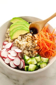 a bowl filled with rice, carrots, radishes and avocado