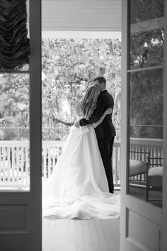 a bride and groom kissing in front of an open door at their wedding venue on the porch