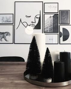 black and white christmas decorations with candles on a wooden table in front of framed pictures