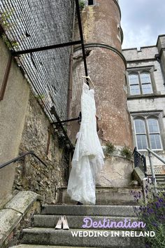 a wedding dress hanging on the stairs outside an old castle