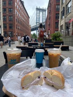 a sandwich cut in half sitting on top of a table next to two cups of coffee