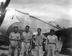 four men standing in front of an airplane