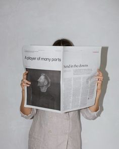 a woman holding up a newspaper in front of her face